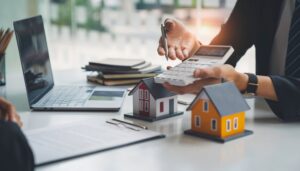 Navigating Rent Control for Landlords in California 2 man holding calculator with wooden house models on a table